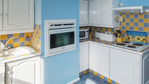 Een keuken met witte kastjes, een ingebouwde oven, een magnetron en een fornuis.