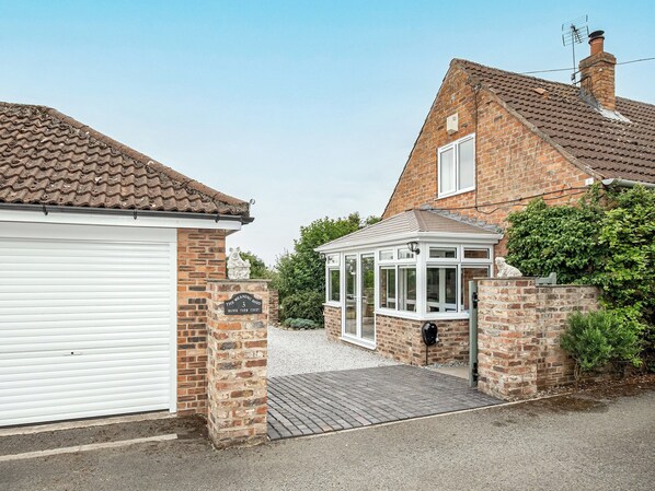 A brick house with a white garage door, a conservatory, and a stone plaque.
