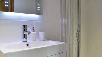 A bathroom with a white sink, a mirror, and a glass shower enclosure.