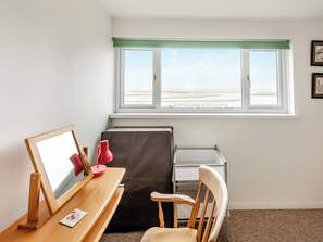 A room with a desk, chair, and a window with a view of the beach.