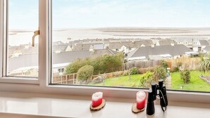 A window view of a coastal town with houses, a beach, and a clear sky.