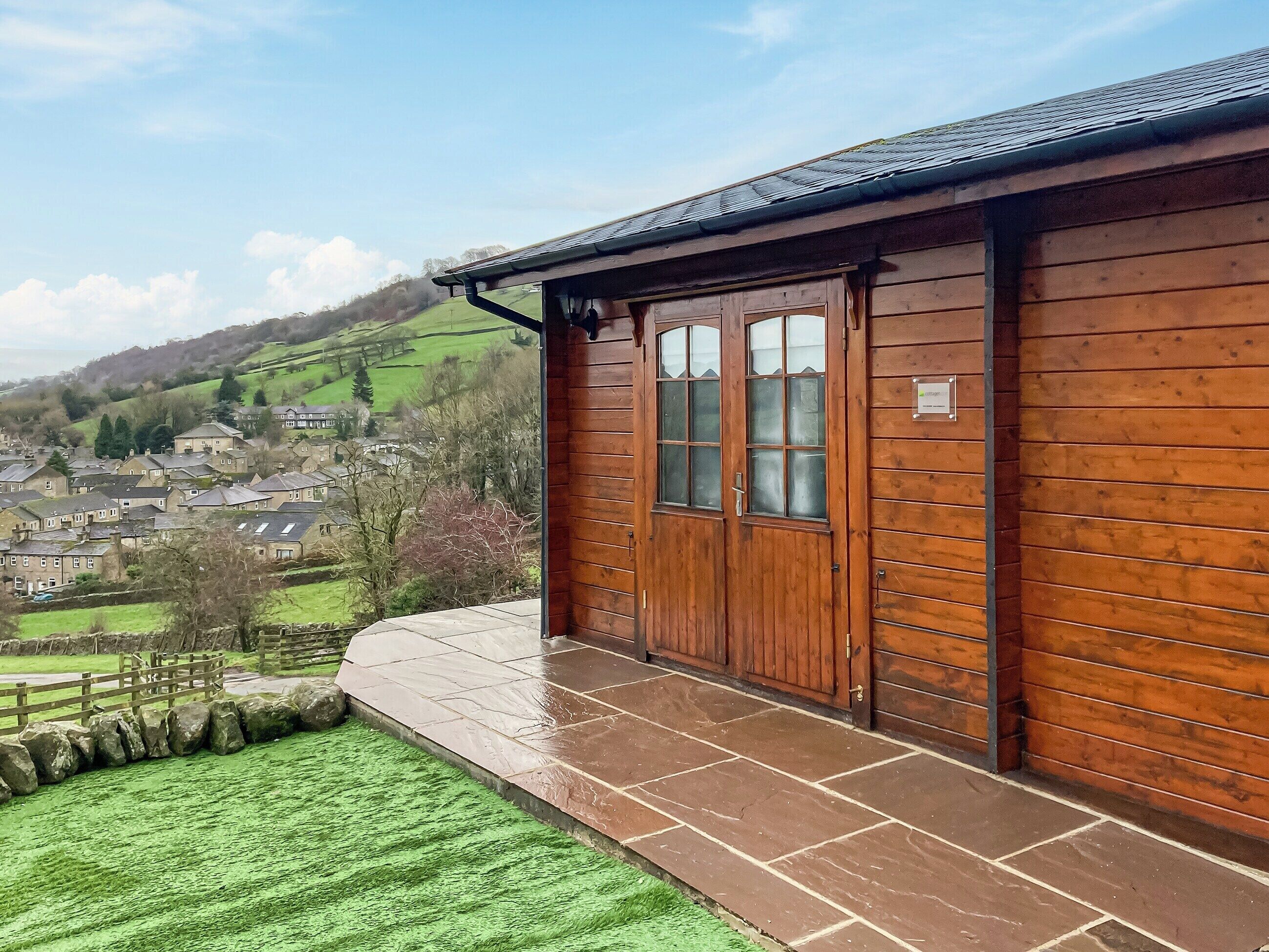 A wooden building with a stone-paved entrance and a view of a village.