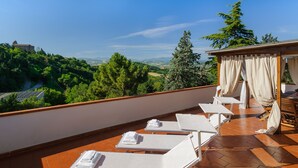 A rooftop terrace with white lounge chairs, a pergola with white curtains, and a scenic view of a hilly landscape. - Villa Mery, Holiday house in the hills of the Rimini Riviera, with private pool (Mondaino)