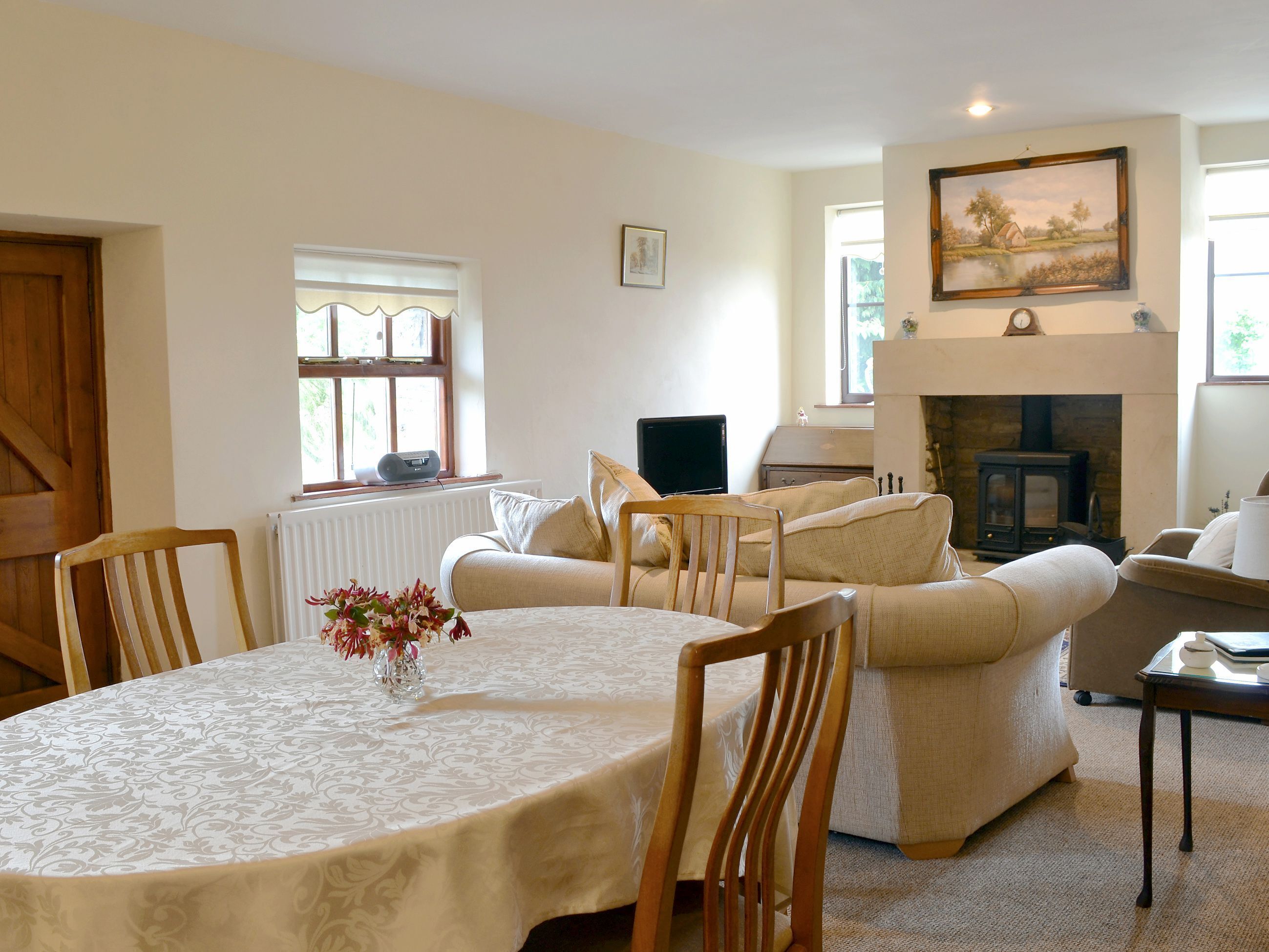 A cozy living room with a fireplace, a dining table with chairs, and a sofa.