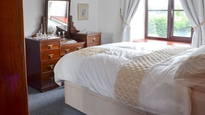 Un dormitorio con cama, cómoda, espejo y ventana con cortinas.