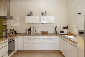 A modern kitchen with white cabinets, stainless steel appliances, and a beige countertop. - Casa Turbolina  | Beautiful Country House with Pool, BBQ & Stunning Valley & Sea Views (Algarrobo)