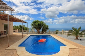 A swimming pool with a view of the sea, surrounded by palm trees and a white fence. - Casa Turbolina  | Beautiful Country House with Pool, BBQ & Stunning Valley & Sea Views (Algarrobo)