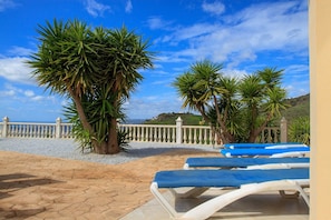 A terrace with lounge chairs, palm trees, and a view of the landscape. - Casa Turbolina  | Beautiful Country House with Pool, BBQ & Stunning Valley & Sea Views (Algarrobo)