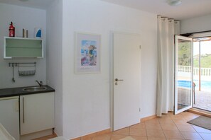A room with a kitchenette, a door leading to a balcony, and a framed picture on the wall. - Casa Turbolina | Beautiful Country House with Pool, BBQ & Stunning Valley & Sea Views (Algarrobo)