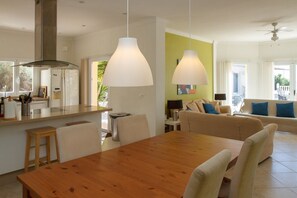 A modern kitchen with a wooden dining table and chairs, a bar area, and a living space with a sofa and a coffee table. - Casa Turbolina  | Beautiful Country House with Pool, BBQ & Stunning Valley & Sea Views (Algarrobo)