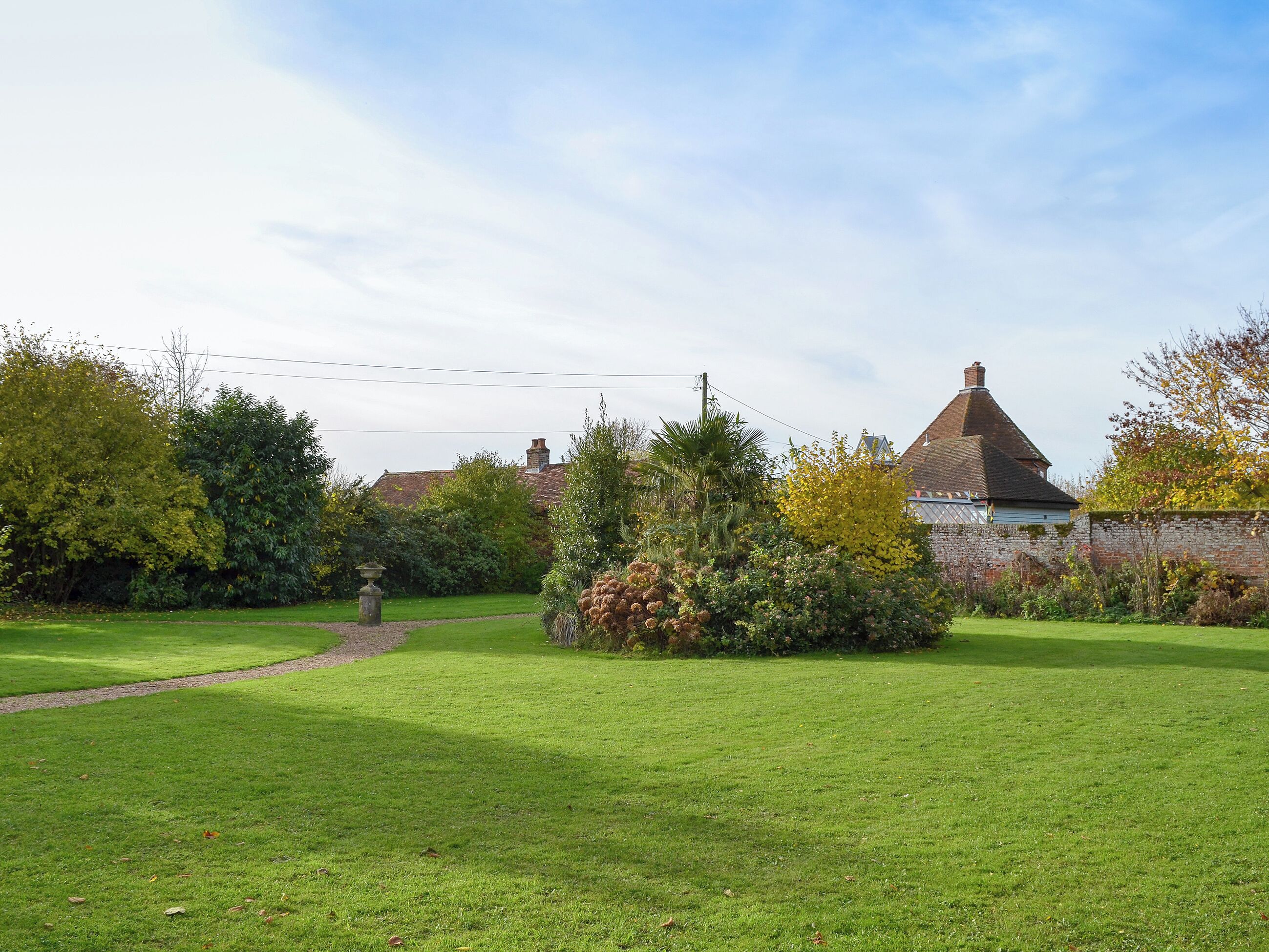 A well-maintained garden with a stone pathway leading to a traditional house with a tiled roof.
