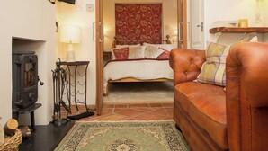 A cozy bedroom with a bed, a leather sofa, a fireplace, and a television on the wall. - Gamekeeper's Cottage (Staple, near Wingham)
