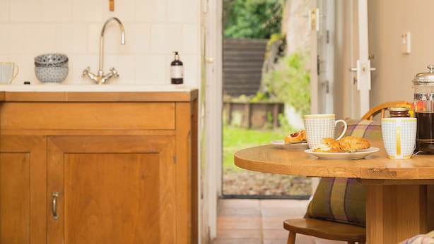 A kitchen with wooden cabinets, a sink, and a window overlooking a garden. - Gamekeeper's Cottage (Staple, near Wingham)