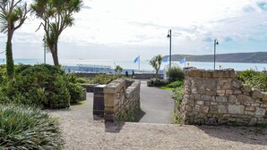 A coastal pathway leading to a stone wall with a view of the sea and flags. - 3 bedroom accommodation in Penzance (Penzance)