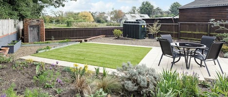 Un patio trasero con un jardín, césped y diversas plantas.