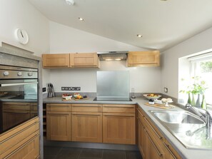 Una cocina moderna con armarios de madera, electrodomésticos de acero inoxidable y un ventanal que proporciona luz natural.