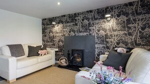 A living room with a fireplace, two white sofas, and a patterned wall. - 2 bedroom accommodation in Blythburgh, near Southwold (Blythburgh, near Southwold)
