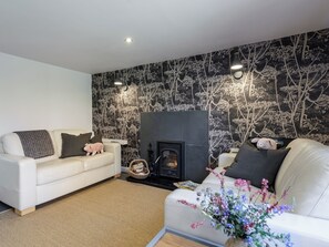 A living room with a fireplace, two white sofas, and a patterned wall. - 2 bedroom accommodation in Blythburgh, near Southwold (Blythburgh, near Southwold)