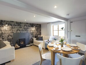 A modern living room with a fireplace, a dining area with breakfast set, and a large window. - 2 bedroom accommodation in Blythburgh, near Southwold (Blythburgh, near Southwold)