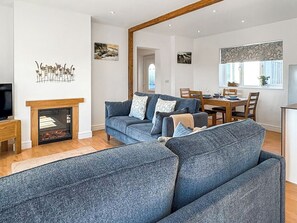A living room with a fireplace, a sofa set, a dining area, and artwork on the walls. - 2 bedroom accommodation in Kentisbury, near Barnstaple (Kentisbury, near Barnstaple)