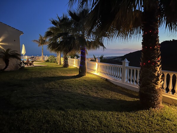 A well-lit outdoor area with a white fence, palm trees, and a view of the ocean. - Casa Bonita - 4 bedroom Country House in Authentic Andalucia, Malaga (Algarrobo)