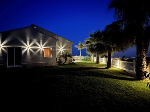 Um edifício com varanda e vista para o mar à noite.