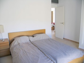 Ein Schlafzimmer mit einem Bett, einem Nachttisch und einer Tür zu einem anderen Raum.