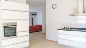 A modern kitchen with white cabinetry, a built-in oven, and a clock on the wall. - Casa Bonita - 4 bedroom Country House in Authentic Andalucia, Malaga (Algarrobo)