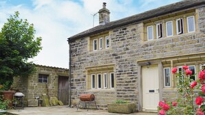 A stone house with a patio, a barbecue, and a garden with roses. - Little Grans Cottage (Ickornshaw, near Cowling)