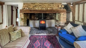 A cozy living room with a stone fireplace, striped sofas, and a patterned rug. - 3 bedroom accommodation in Sternfield, near Aldeburgh (Sternfield, near Aldeburgh)