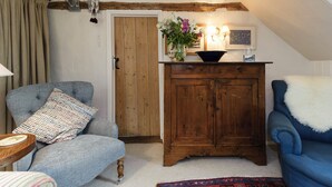 A cozy living room with a blue armchair, a wooden cabinet, and a small table. - 3 bedroom accommodation in Sternfield, near Aldeburgh (Sternfield, near Aldeburgh)