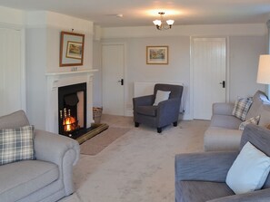 A living room with a fireplace, two armchairs, a sofa, and a floor lamp.