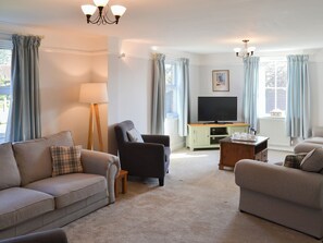 A living room with a sofa, armchair, and a television on a cabinet.