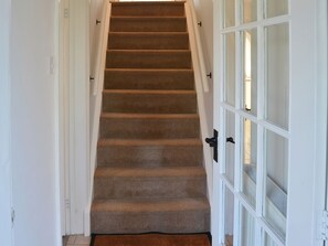 A carpeted staircase leading to a door with a glass panel. - 4 bedroom accommodation in Stalham (Stalham)