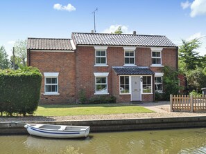 A two-story brick house with a tiled roof, a front door, and a small porch. - 4 bedroom accommodation in Stalham (Stalham)