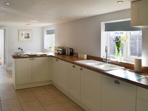 A modern kitchen with white cabinets, a wooden countertop, and a large window with a view.