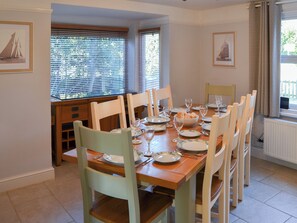 A dining room with a wooden table set for six, surrounded by six chairs.