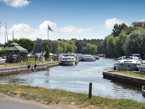 A canal with boats docked, a small pavilion, and a flag.
