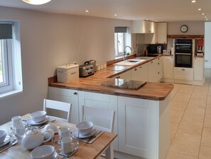 A modern kitchen with white cabinetry, a wooden countertop, and a dining area set for four.