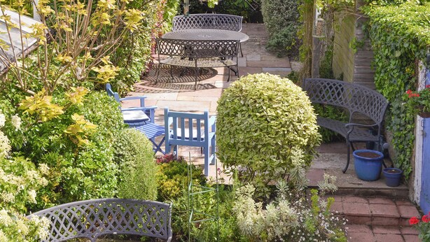Una terrazza giardino con mobili da esterno, un pergolato e diverse piante.