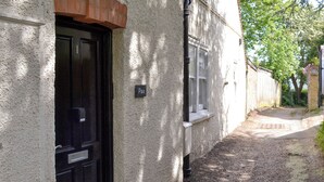 Un stretto vicolo con una porta nera e una finestra su un muro strutturato.