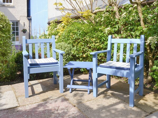 Two blue chairs with cushions, a small table, and a garden with various plants and a tree. - 2 bedroom accommodation in St. Margarets at Cliffe, near Dover (St. Margarets at Cliffe, near Dover)
