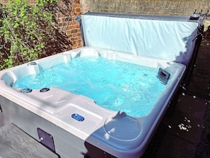 Un bain à remous doté d’une couverture, d’un panneau de commande et d’une petite fenêtre.