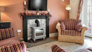 Ein Wohnzimmer mit Kamin, einer Couch, einem Sessel und einem Fernseher.