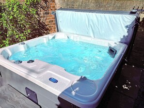 A hot tub with a cover, a control panel, and a small window.