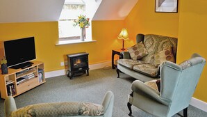 A living room with a television, a sofa, a chair, a lamp, and a fireplace.