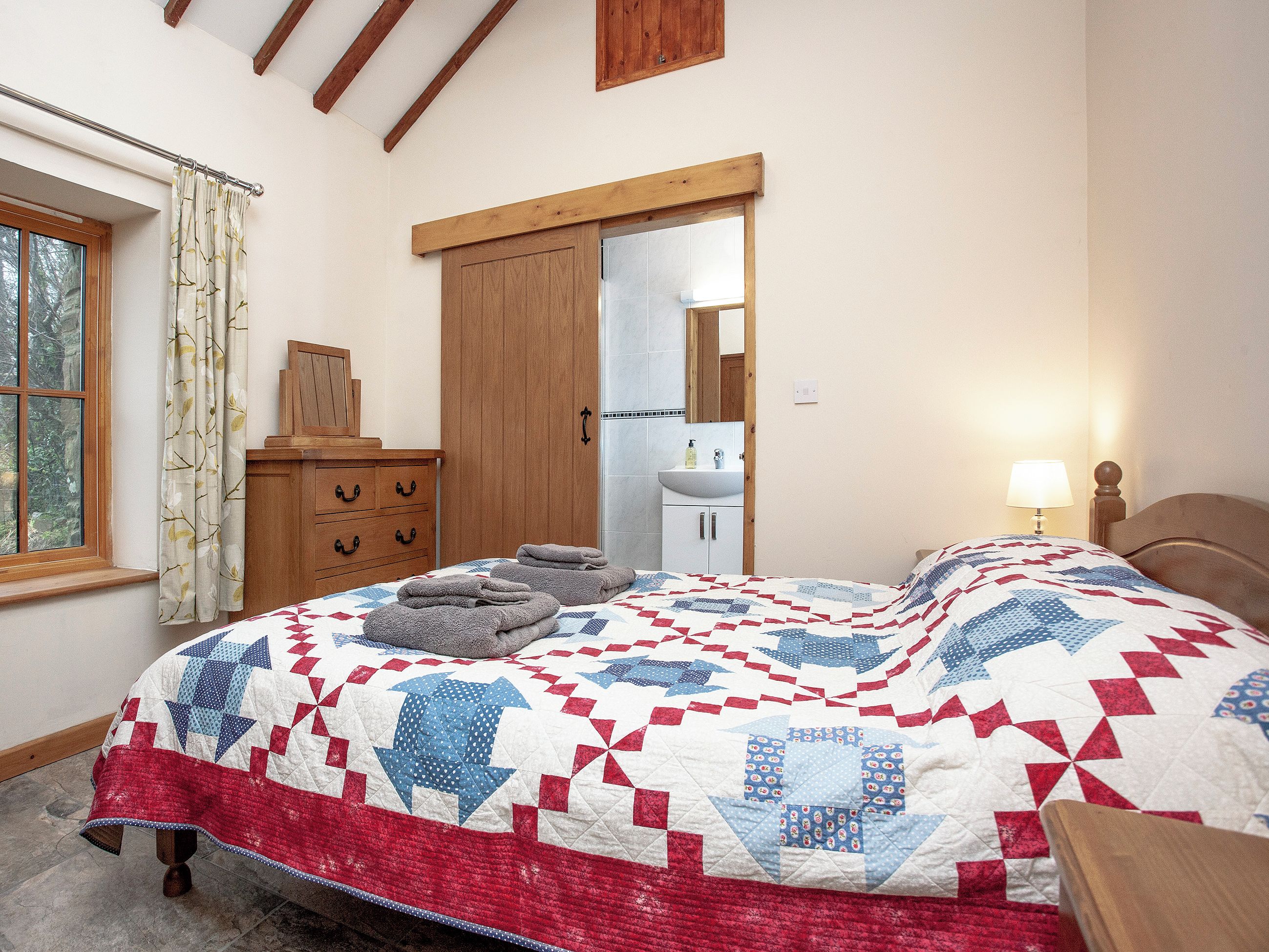 Une chambre à coucher avec un lit, une commode, un miroir et une fenêtre.