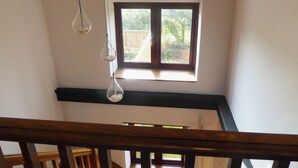 A high-ceiling room with a large window, a wooden staircase, and hanging light fixtures. - 2 bedroom accommodation in Porchfield, near Newport (Porchfield, near Newport)
