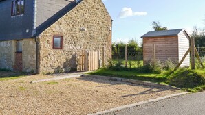 A stone house with a sloped roof and a small wooden shed. - 2 bedroom accommodation in Porchfield, near Newport (Porchfield, near Newport)