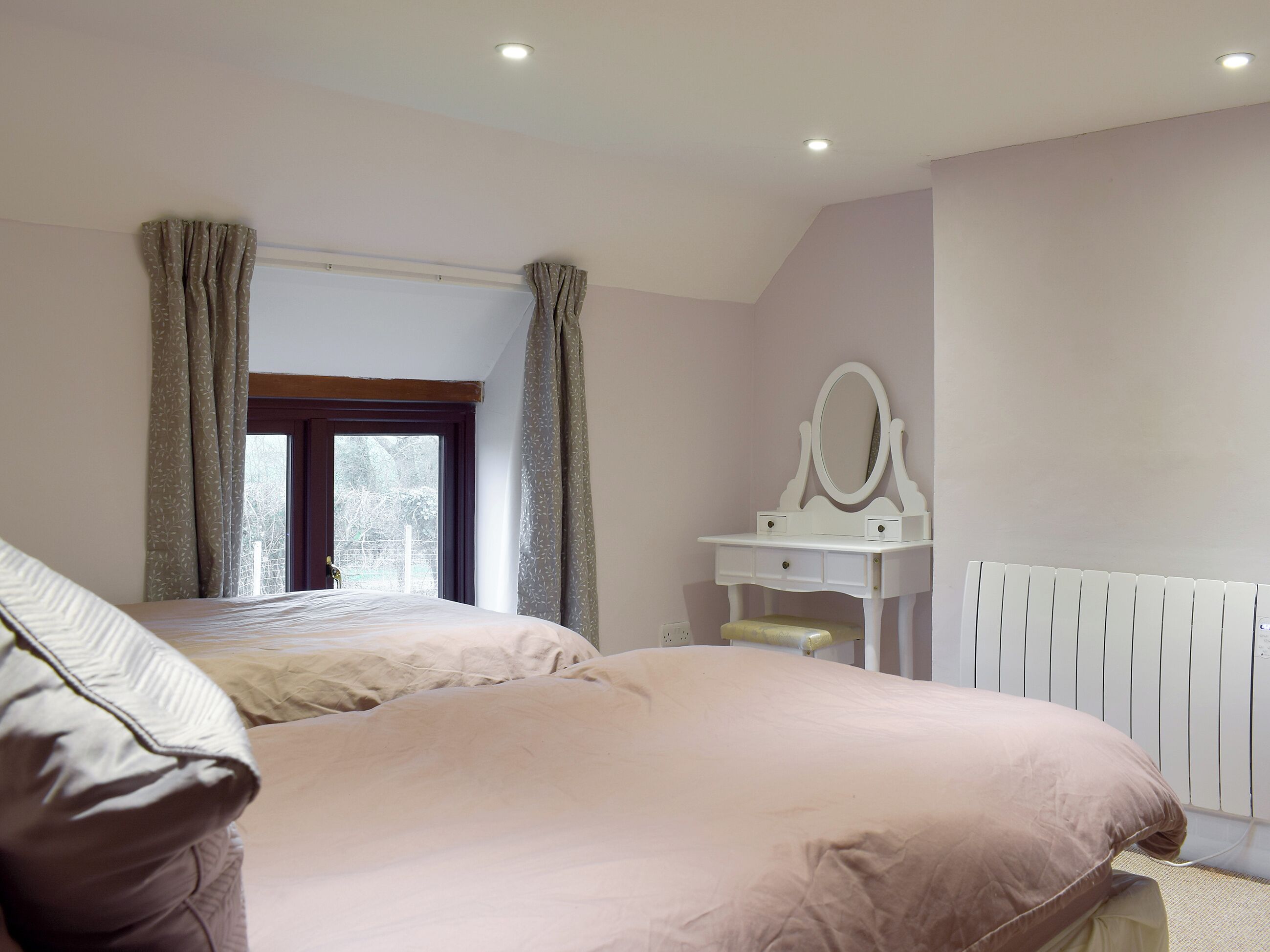 Une chambre à coucher avec un lit, une commode avec un miroir et une fenêtre avec des rideaux.